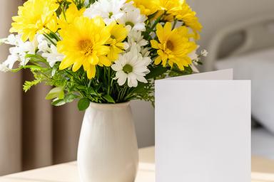 Cheerful yellow and white get well flowers beside a greeting card