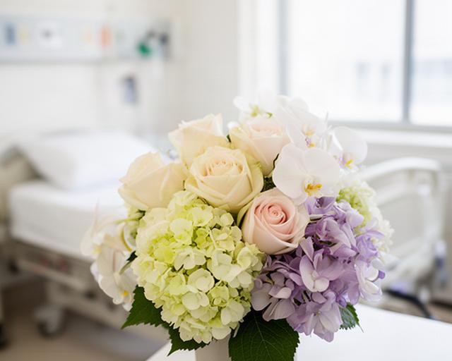 Low-pollen bouquet of pale roses, hydrangeas and orchids in a bright hospital room